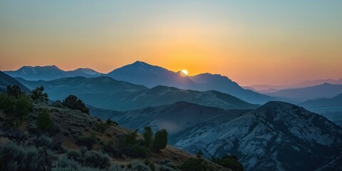 A scenic view of mountains with the partially eclipsed sun rising behind them. 
