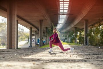 A fit sportswoman in shape is stretching her outside.