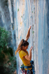 A woman climbs a rock, a strong girl trains strength and endurance, extreme sport, rock climbing..