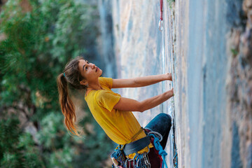 A young and strong woman is rock climbing on a rock. .