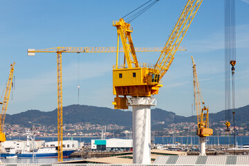 Fototapeta na wymiar This image showcases several large yellow industrial cranes towering over a construction site with a clear blue sky
