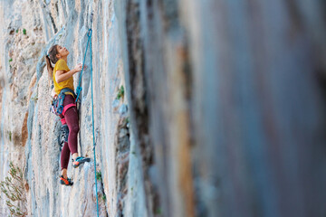 Climber overcomes challenging climbing route. A girl climbs a rock. Woman engaged in extreme sport....