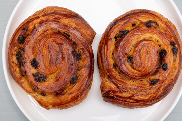 Fototapeta premium Breakfast in bakery with fresh baked coffee buns sweet pastry with raisins, morning food close up
