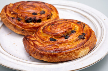 Breakfast in bakery with fresh baked coffee buns sweet pastry with raisins, morning food close up