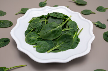 Fresh green baby Spinach leaves, diet and health concept, weight loss, spinach on ceramic plate, copy space