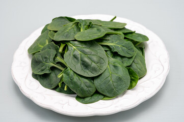 Fresh green baby Spinach leaves, diet and health concept, weight loss, spinach on ceramic plate, copy space