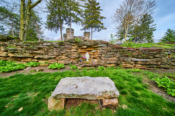 Rustic Stone Wall with Religious Statue and Spring Flowers