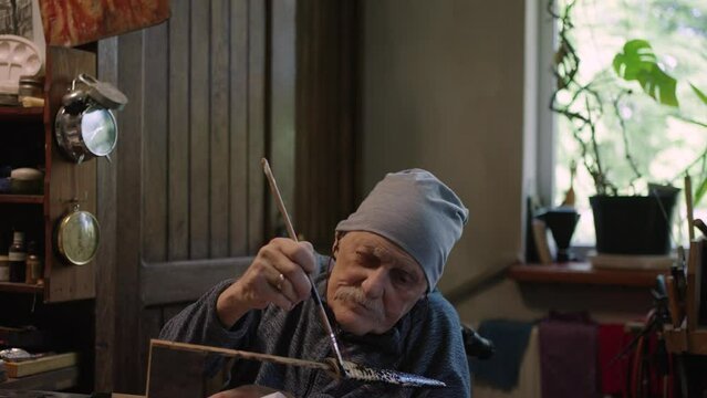 Elderly male master works in his workshop restoring japanese deba knife sheath