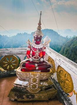 Red glass Meditation Buddha statue ornate with golden jewels at the hilltop pagoda of the Wat Tham Sua aka Tiger Cave Temple of Krabi Thailand