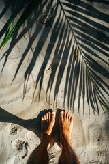 bare female feet on a sandy surface, with a palm leaf on the background, summer wallpaper