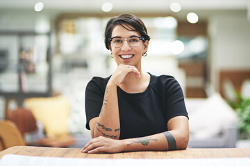 Design, portrait and smile with woman at desk in office for artistic or creative occupation. Company, glasses and wooden table with happy young designer in workplace for start of career or project