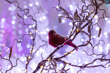A freezing bird perches on a twig as purple lights illuminate the snowy branch