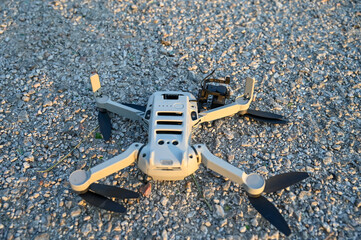 Crashed and damaged drone. Broken arms and camera gimbal of drone on asphalt road. Drone fell to the ground. Accident during flight.  