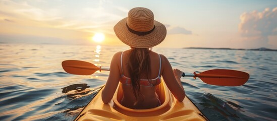 Sunset kayaking  young woman in straw hat enjoying active outdoor travel in beautiful blue sea