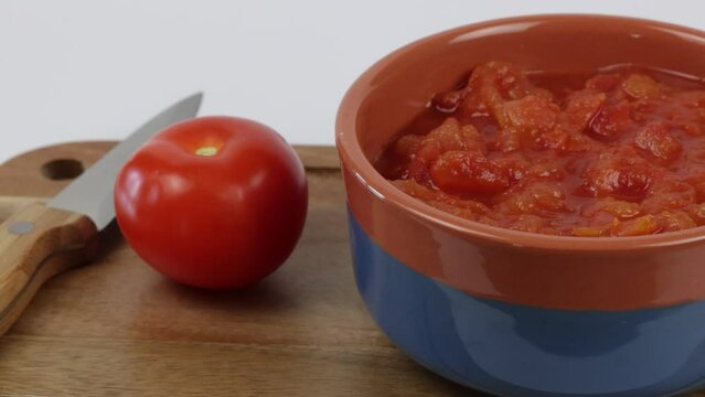 bol de tomates concass&eacute;es, en gros plan, sur une planche &agrave; d&eacute;couper