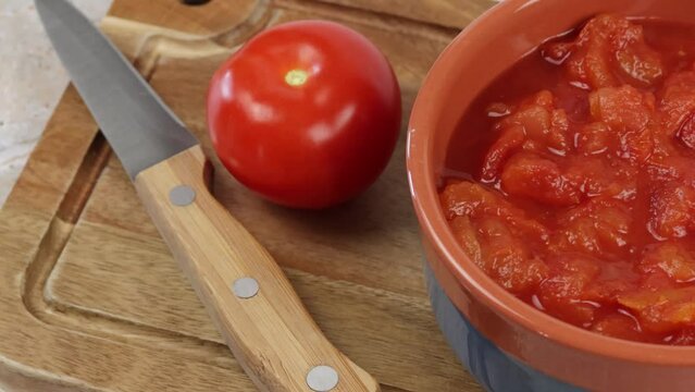 bol de tomates concass&eacute;es, en gros plan, sur une planche &agrave; d&eacute;couper