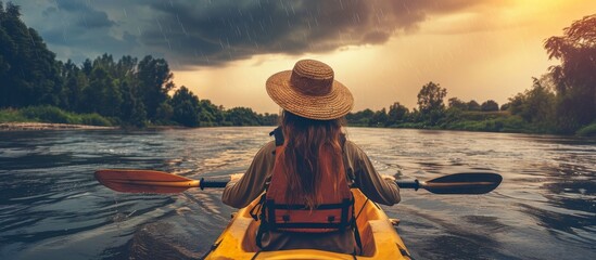 Adventurous woman kayaking in stormy river at sunset during rain, outdoor travel concept