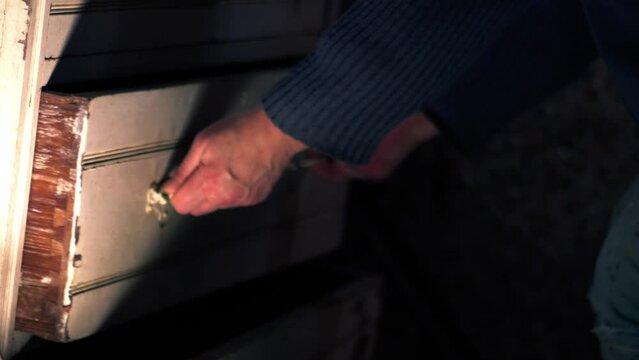 Hand opening drawer of old vintage cabinet to look for items 