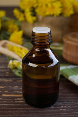 Composition with essential oil and dandelion flowers on dark table. Flower essential oil. Herbal medicine. Side view.           