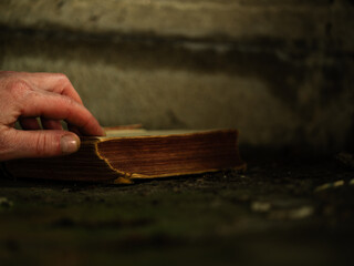 Hand opening old worn book in window light 