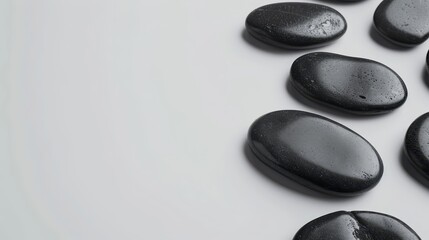 A pristine flat lay of black spa stones neatly arranged on a white background, offering a clean and simple backdrop with space for text