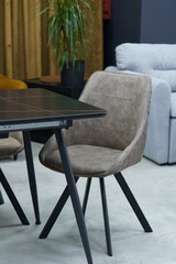 Black wooden table complete with beige wooden chairs with soft fabric upholstery. White candle on the table