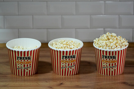 Popcorn in a striped box on a wooden table. Selective focus. Delicious fast food