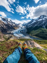 the viewer's legs are stretched out, relaxing on a grassy slope amidst a breathtaking mountainous landscape
