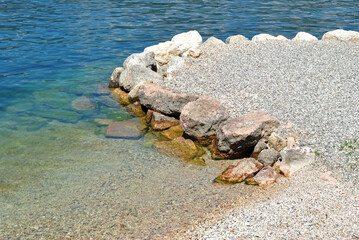 Close Up of Deserted Stone Beach beside calm Italian Lake 