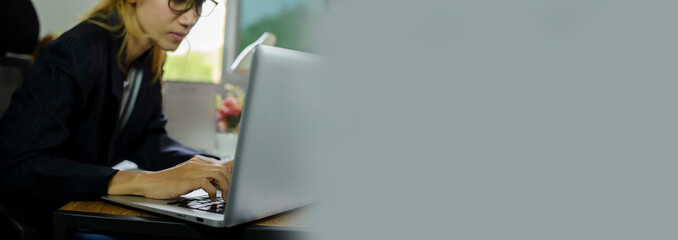 Businesswoman hand typing laptop. Person side view of Woman working online and searching business project at home office-Banner image.