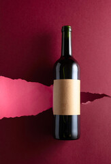 Bottle of red wine with old empty label on a dark red background.