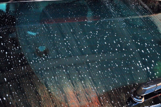 Car washing. Drops from soap solution on car glass