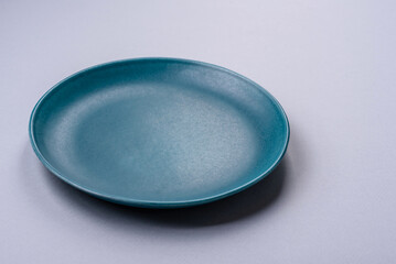 An empty plate on a gray concrete background with copy space - obrazy, fototapety, plakaty
