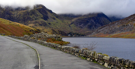 Curved road by the serene body of water with mountains. Wales, UK