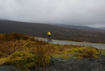 A cyclist riding on a road in a mountainous area. Landscape in Ireland.