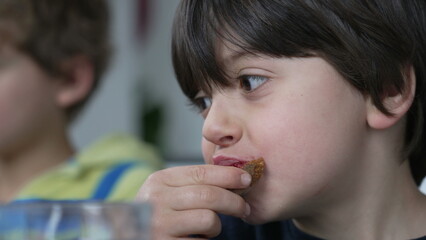 Close-up face of small boy eating bread with jelly for breakfast, candid kid snacking carb food - obrazy, fototapety, plakaty