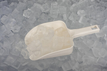 A scoop of ice is sitting on top of a pile of ice cubes