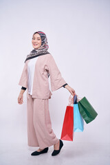 Smiling Asian hijab fashion girl holding shopping bags isolated over white background - shopping, announce, sale, business and lifestyle concept