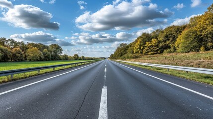 Fototapeta premium A long, empty highway with a few trees in the background