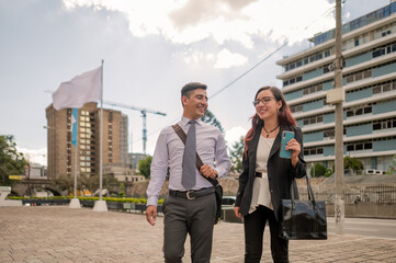 A young man and woman walk happily through the financial center of Guatemala with buildings in the...