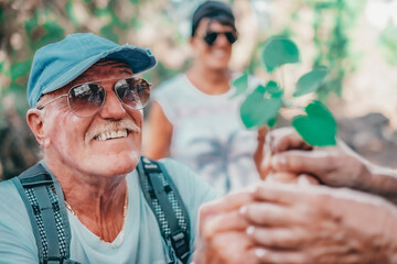 Portrait of old smiling caucasian senior man in outdoors excursion offering a small brunch to a lady