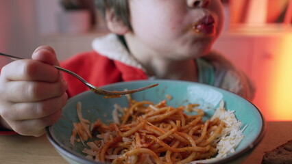 Small boy enjoying plate of pasta for supper, close-up face of 5 year old child eating spaghetti