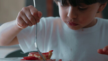 Young Boy Delicately Selecting Strawberry Slices from Cheesecake/ Enjoying Sweet Dessert with Fork...