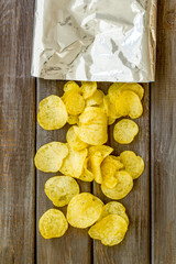 Pack of splashing crispy potato chips, top view. Fast food and snack background