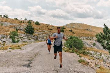 Fototapeta premium A couple dressed in sportswear runs along a scenic road during an early morning workout, enjoying the fresh air and maintaining a healthy lifestyle
