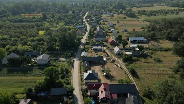 Drone over a typical Masovian village in central Poland with greenery, and river in the background