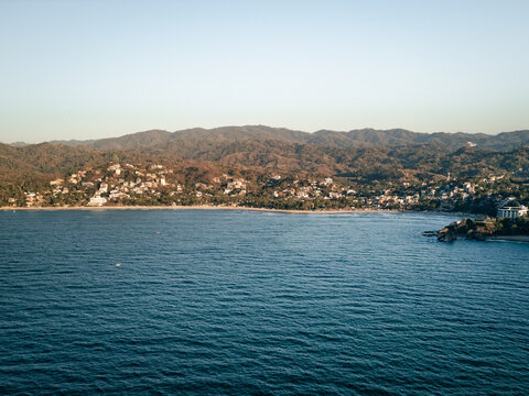 View of Sayulita Mexico beach looking east. Aerial view at sunset with waves crashing at point.
