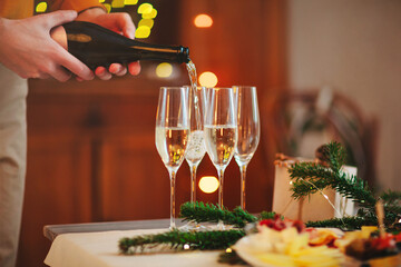 Glasses of champagne on wooden table with candles against blurred wall with Christmas decoration