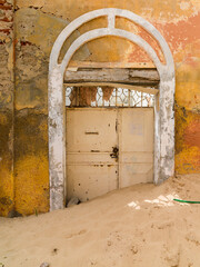 la porte ensablée d'un ancien bâtiment colonial en ruine dans la vieille ville de Saint Louis au Sénégal en Afrique de l'Ouest - obrazy, fototapety, plakaty