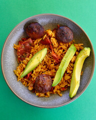 Beef meatballs with spicy rice sun dried tomatoes and sliced avocado.
